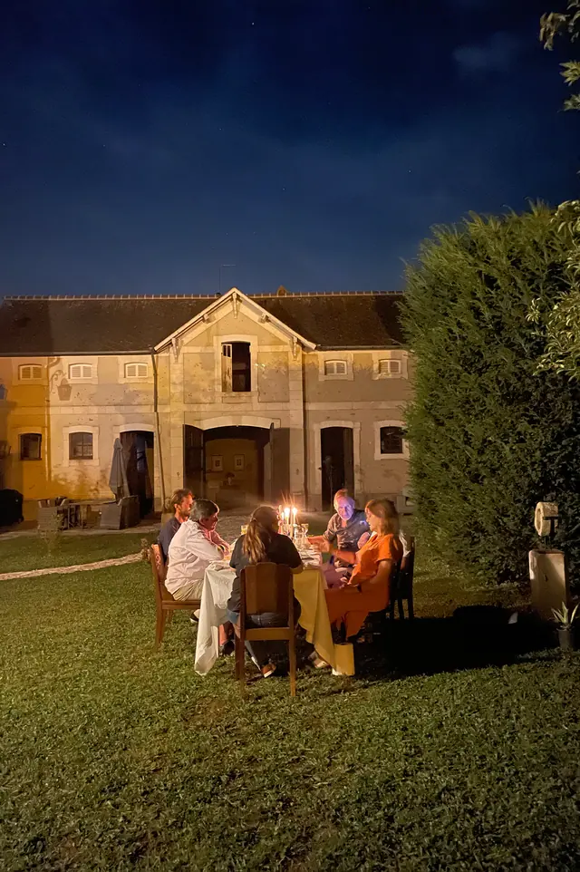 Un dîner aux chandelles servi dans le jardin à la nuit tombée
